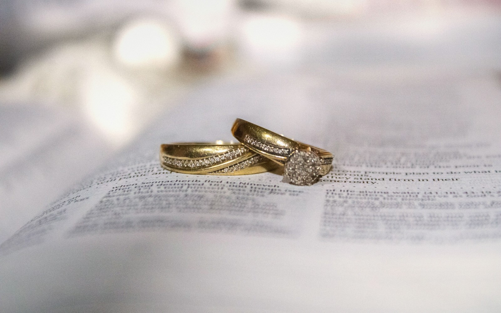 Two gold diamond wedding rings resting on an open book page