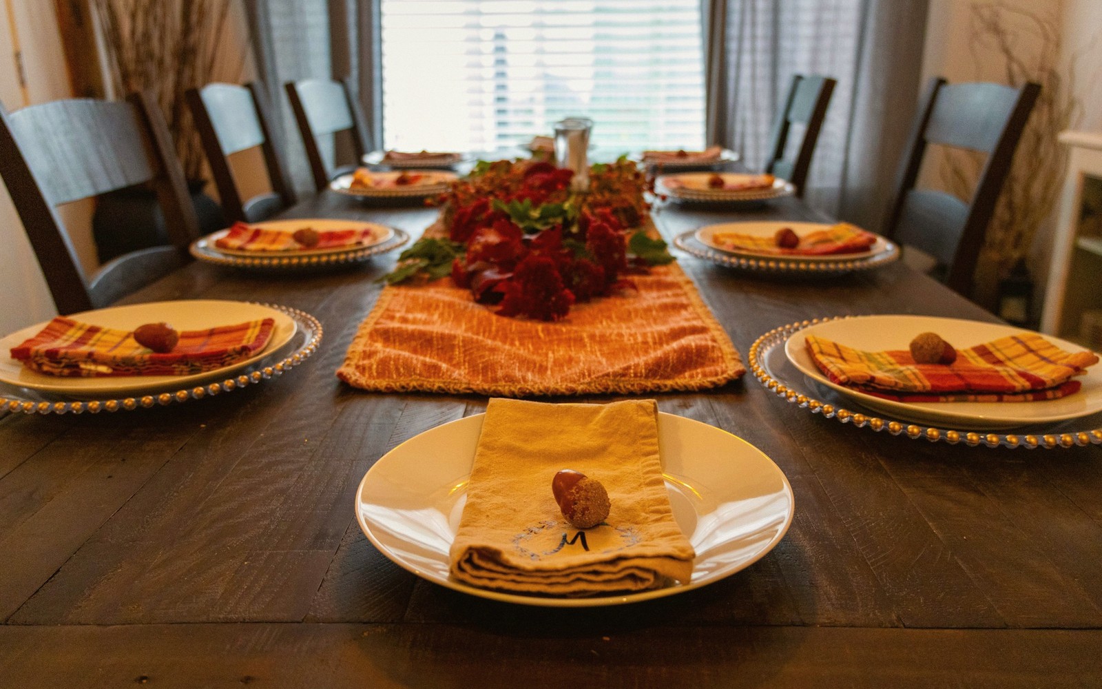Long dining table set with plates, folded napkins and a floral centerpiece runner